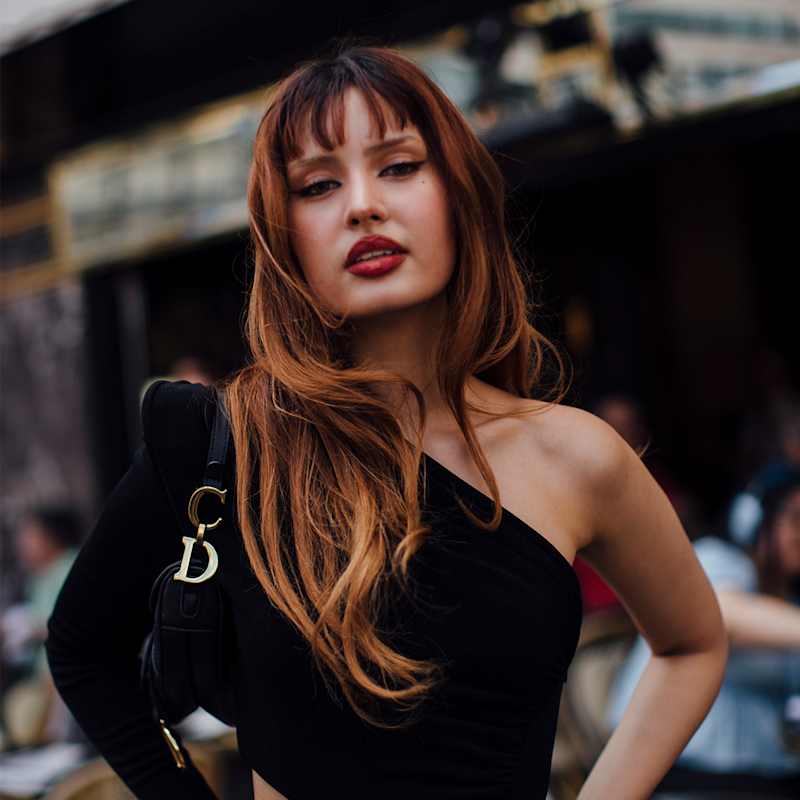 Frau mit kupferroten, langen Haaren und fransigem Pony