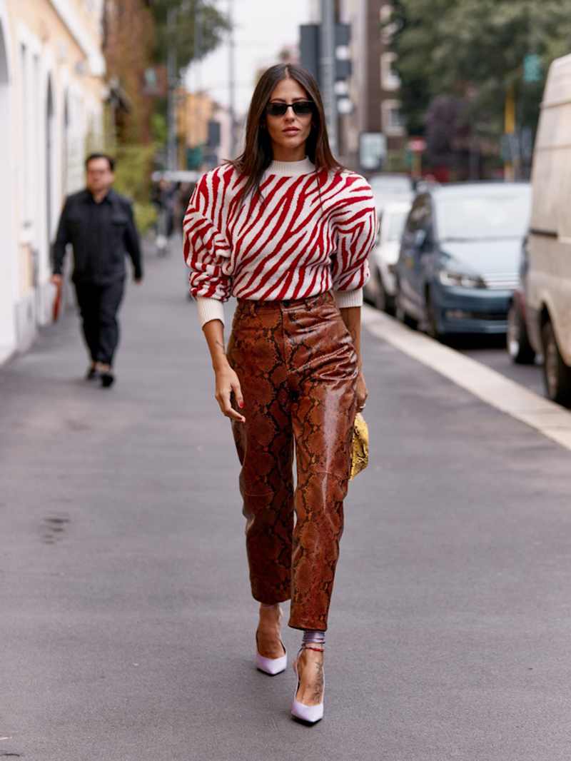 Frau trägt einen rot-weißen Pullover mit Animal Print und eine rote Hose mit Schlangenmuster
