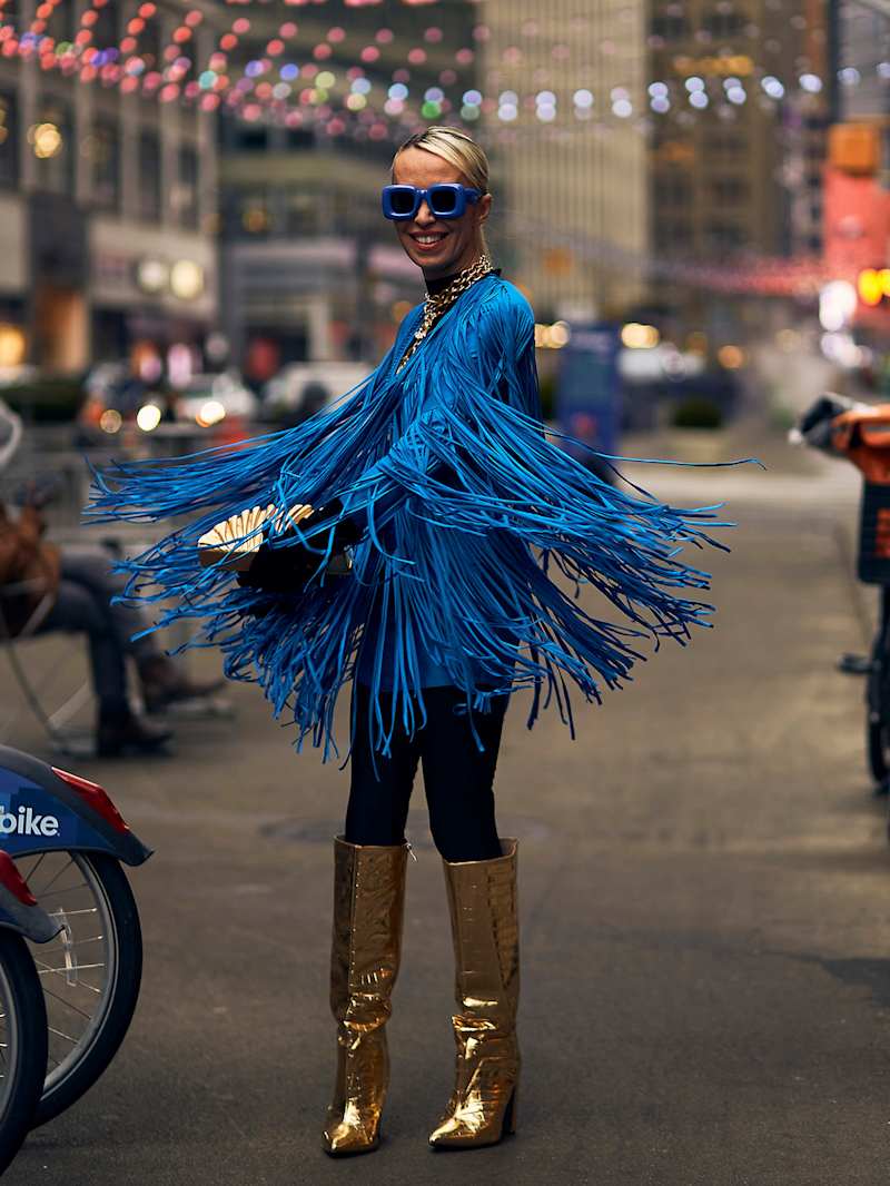 Frau trägt goldene Metallic-Boots zu einem blauen Fransen-Kleid