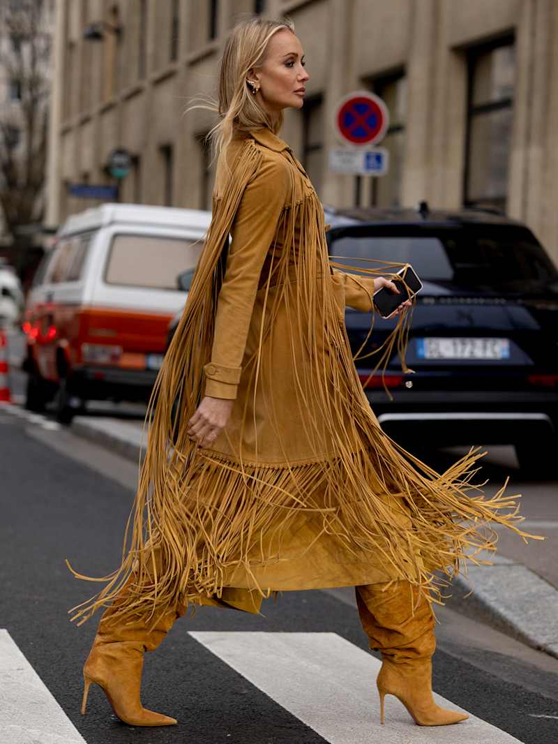 Frau trägt ein Fransenkleid in Hellbraun mit passenden Stiefeln
