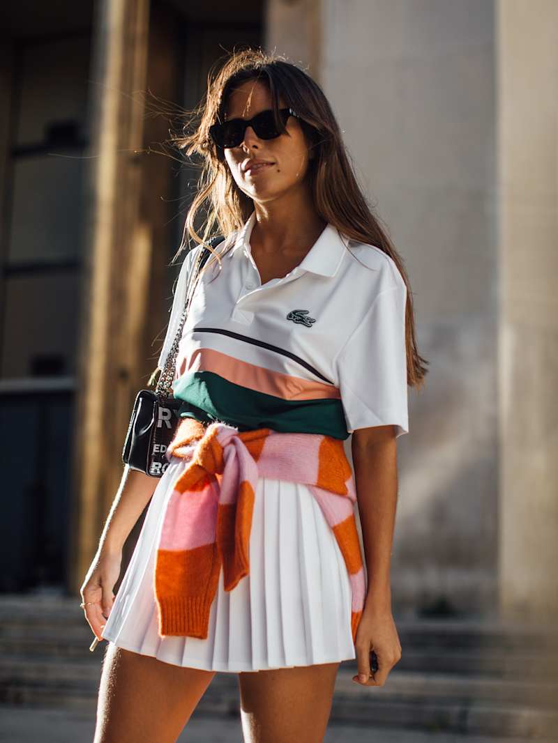 Frau trägt ein sportliches Outfit bestehend aus Tennis-Rock und Polo-Shirt