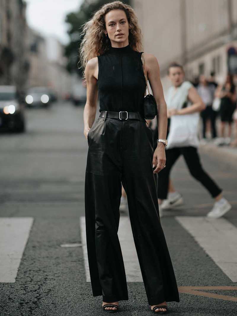 Frau trägt ein All-Black-Outfit mit Lederhose, Top und Accessoires