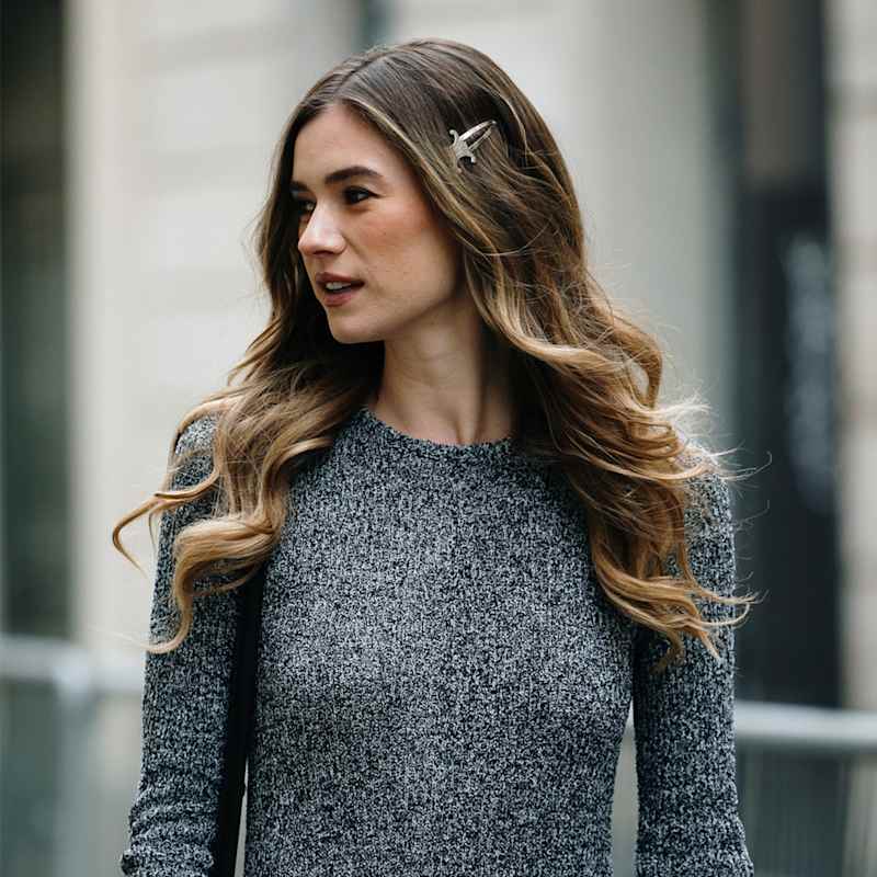 Frau mit dunkelblonden, langen Haaren trägt ein aschblondes Balayage