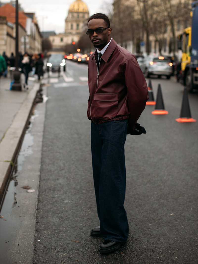 Mann trägt einen Blouson aus weichem Leder in der Farbe Burgunderrot zu einer schwarzen Hose