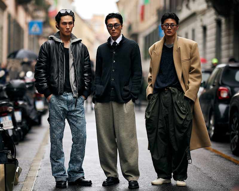 Drei Männer tragen moderne Lederjacken und einen beigen klassischen Wollmantel , kombiniert mit saisonaler Mode für den Herbst/Winter