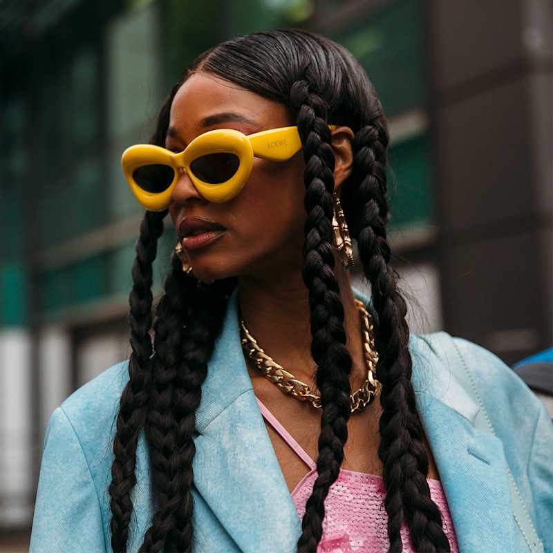 Frau trägt ihre schwarzen Haare in mehreren Flechtzöpfen