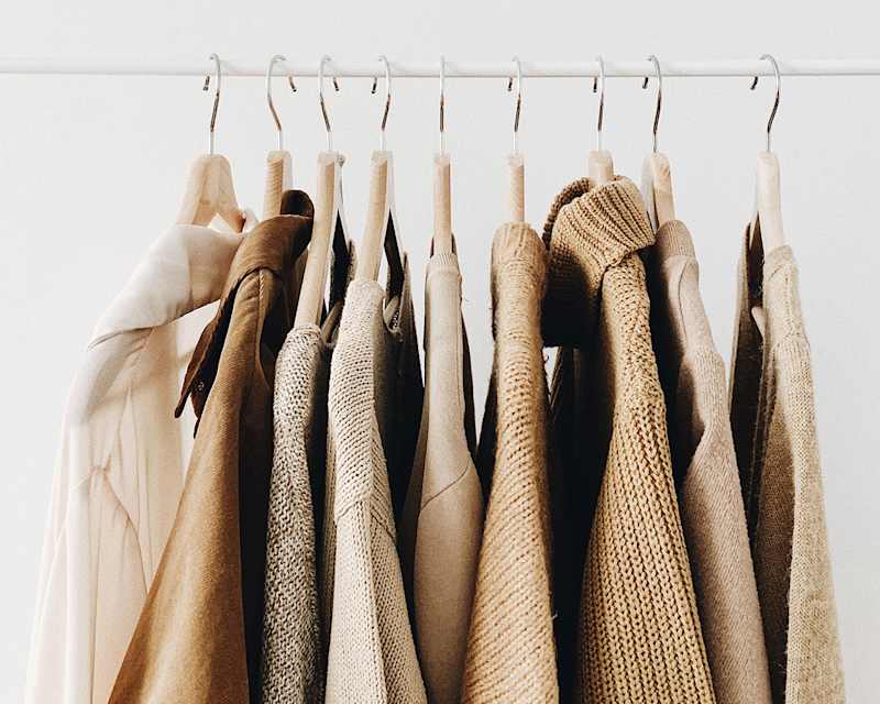 Mehrere beige Oberteile aus verschiedenen Materialien hängen auf einer Kleiderstange