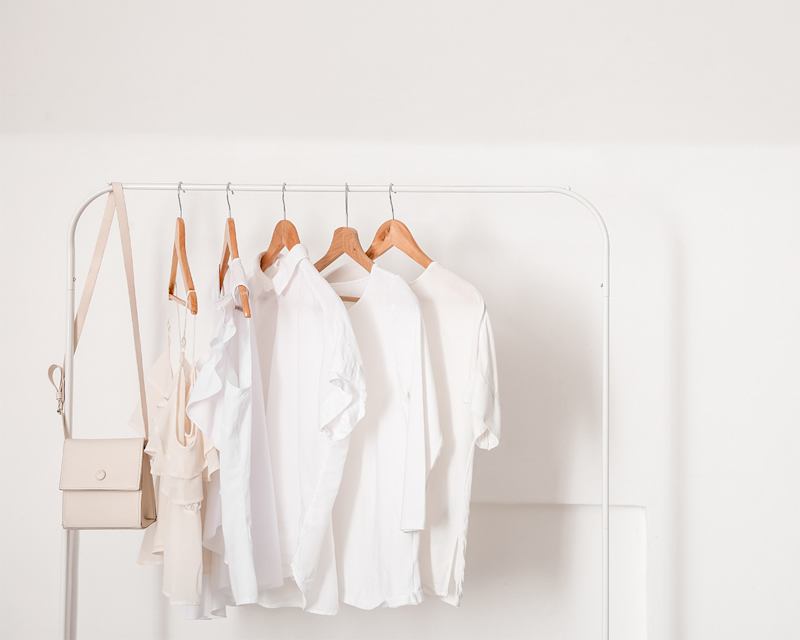 Mehrere weiße Oberteile hängen an einer Wäschestange