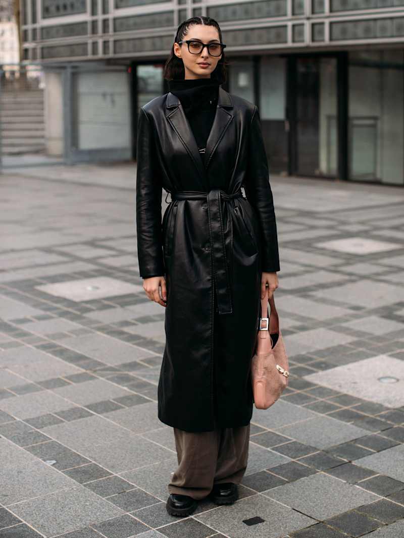 Frau trägt einen schwarzen Ledermantel als Teil eines Winter-Outfits