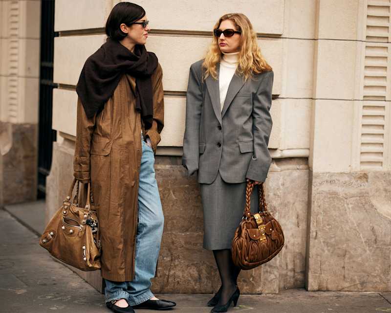 Zwei Frauen tragen Winter-Outfits, ein brauner Mantel und einen grauen Blazer und passender Rock