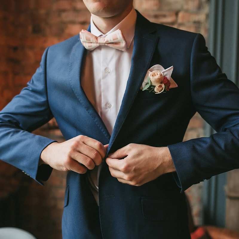 Mann macht sich das Sakko seines blauen Sakkos zu