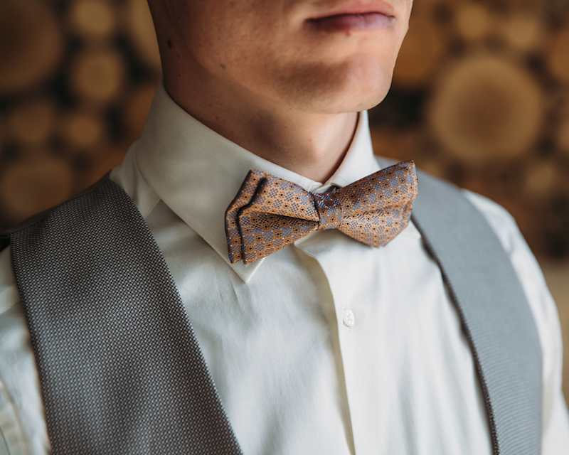 Nahaufnahme von einem Mann, der eine Fliege zu einem weißen Hemd und einer grauen Weste trägt