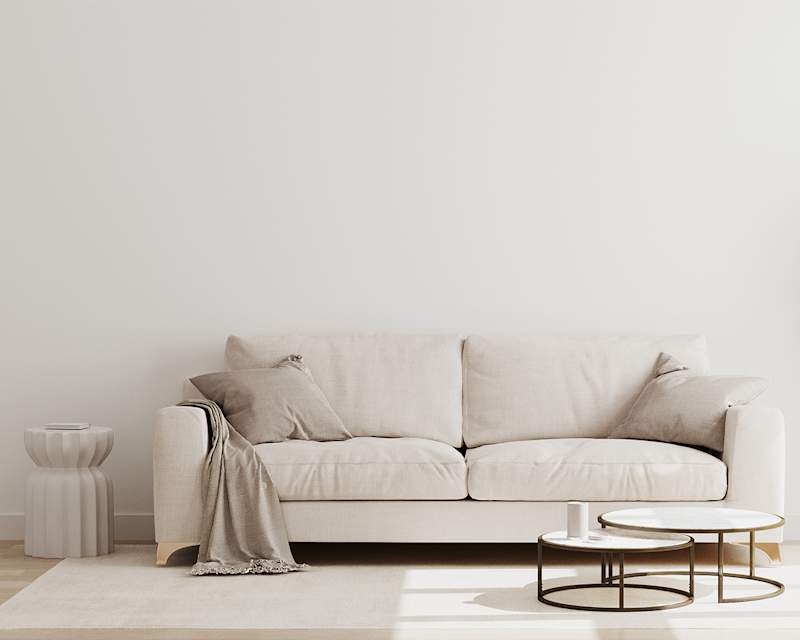 Cremefarbene Couch mit Decke, Beistelltisch und Teppich