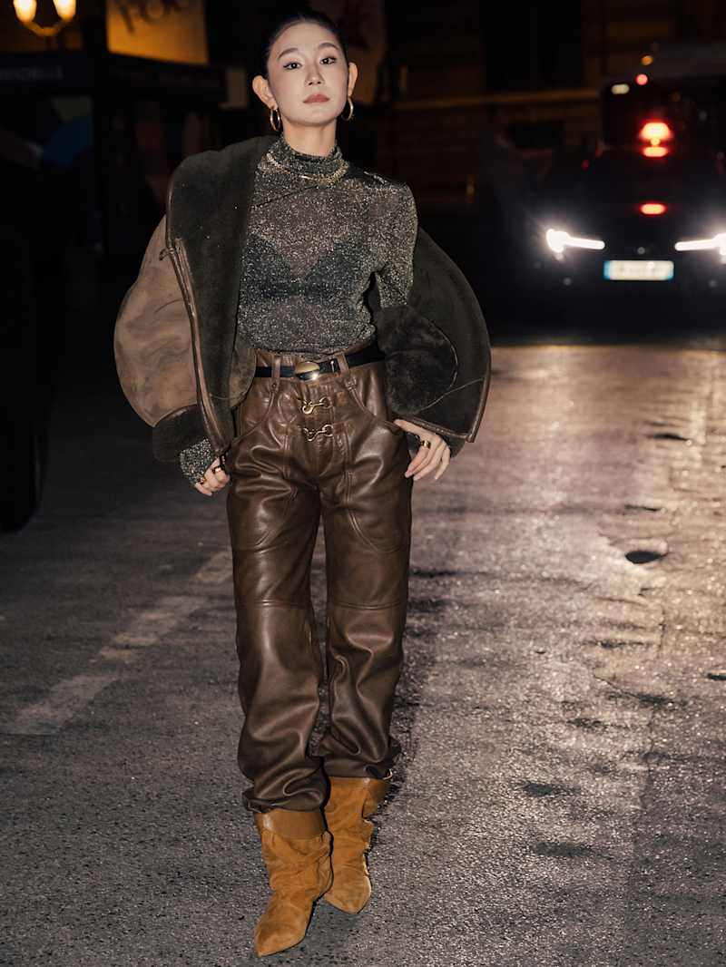 Frau trägt eine braune Lederhose und unter einer braunen Jacke ein Shirt aus Glitzergarn