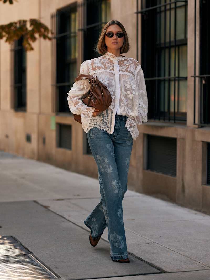 Frau trägt eine hellblaue Jeans mit Applikationen zu einer weißen Spitzenbluse