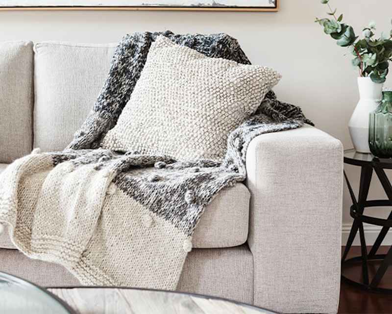 Beiges Sofa mit Kissen und Tagesdecke