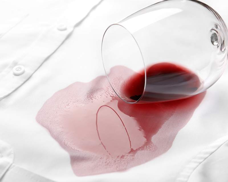 Ausgelaufenes Glas Rotwein auf einem weißen Hemd