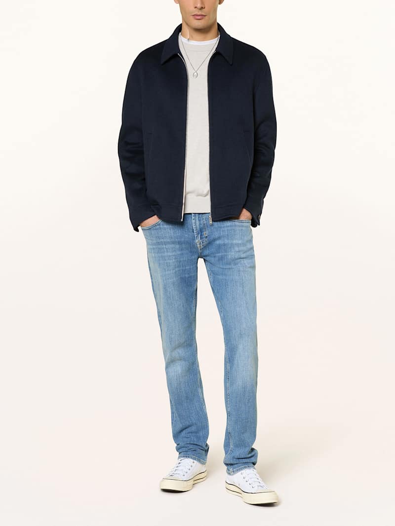 Mann trägt eine Mid-Blue Slim-Fit_Jeans zu einem blauen Overshirt und weißem T-Shirt 