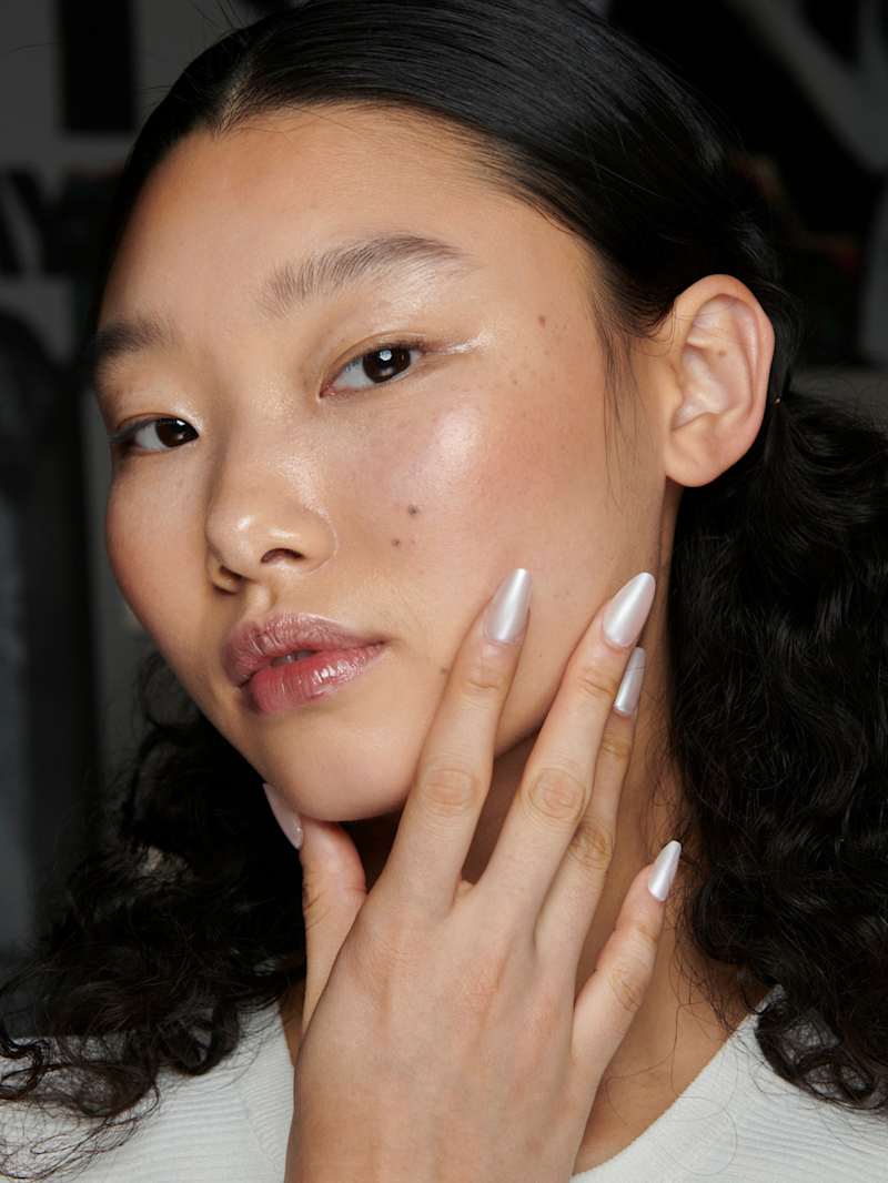 Frau trägt Make-up und weißeFingerägel passend zur Farbe des Jahres in Cloud Dancer