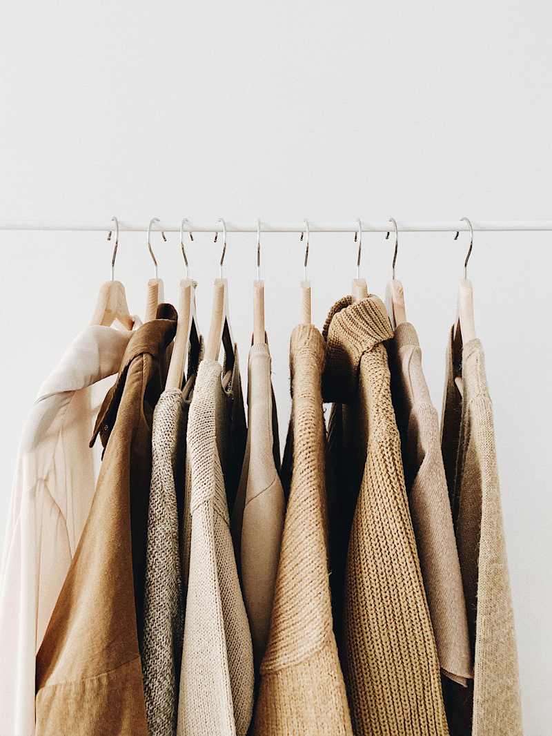 Kleidung und Strickware hängen auf einer Kleiderstange