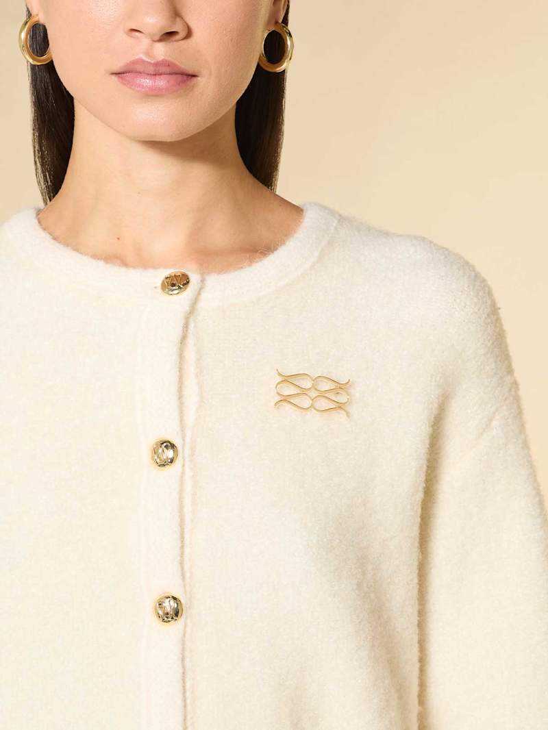 Frau trägt eine goldene Brosche an ihrem hellen Cardigan