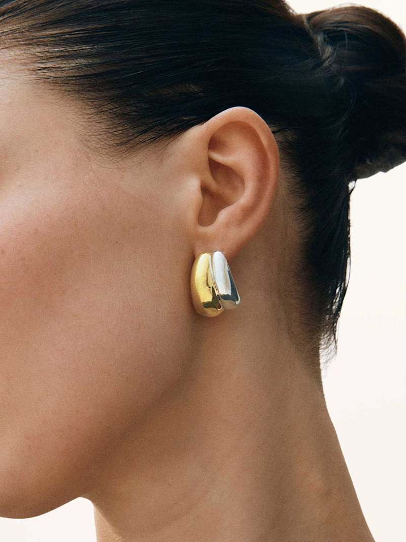 Frau trägt bicolor Ohrringe in Silber und Gold als Schmucktrend