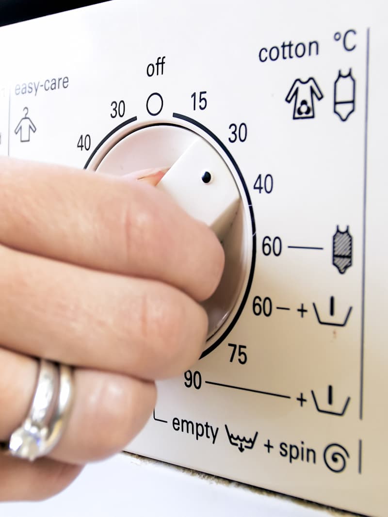 Frau stellt die Temperatur an der Waschmaschine ein