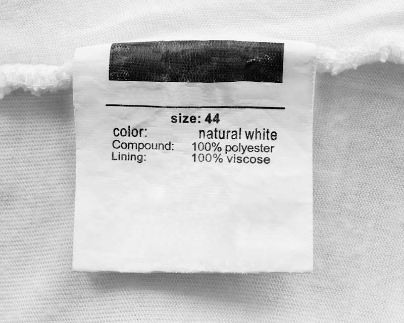 Schild aus einem Kleidungsstück auf dem Size 44 und die Zusammensetzung Polyester steht