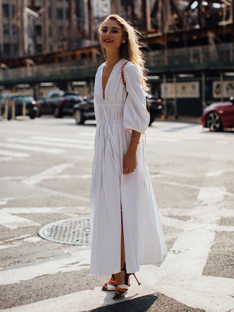 Frau steht auf einer Straße und trägt ein weißes Kleid 