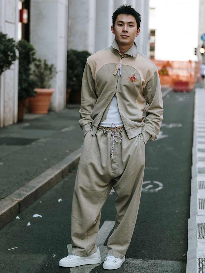 Mann in einem Trainingsanzug aus Polyester in der Farbe Beige trägt dazu weiße Sneaker