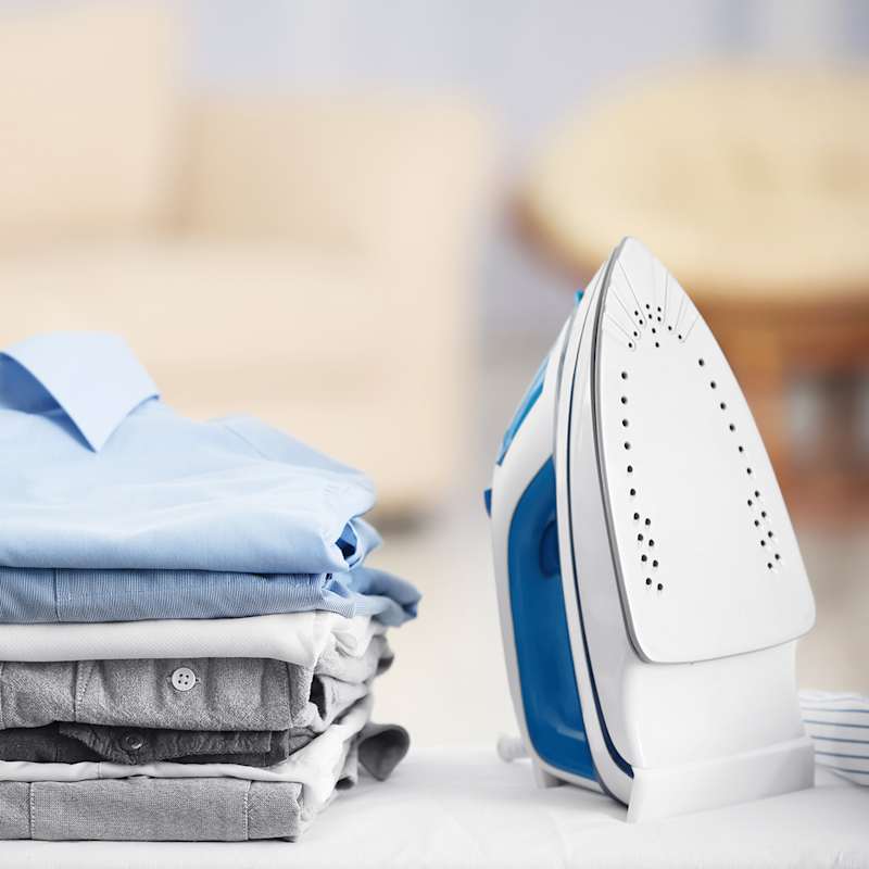 Bügeleisen neben einem Stapel Hemden