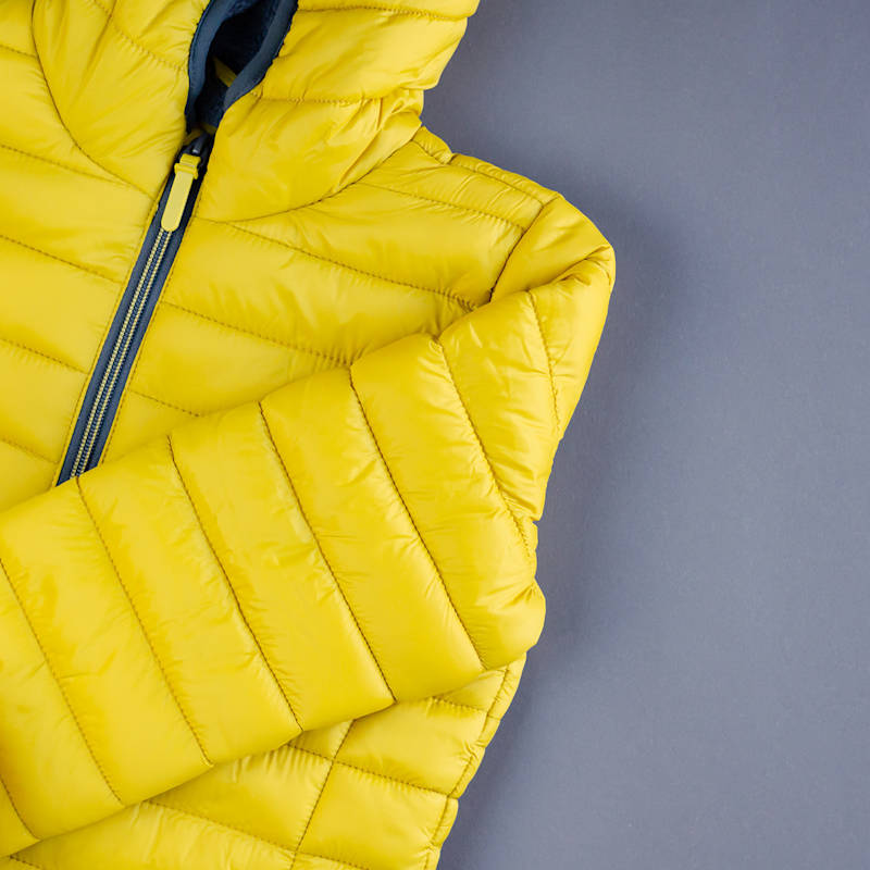 Gelbe Daunenjacke auf neutralem Hintergrund