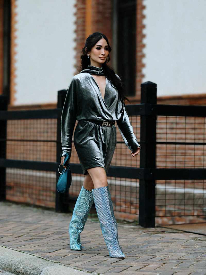 Frau in einem blauen Wickelkleid aus Samt mit Overknee-Schuhen