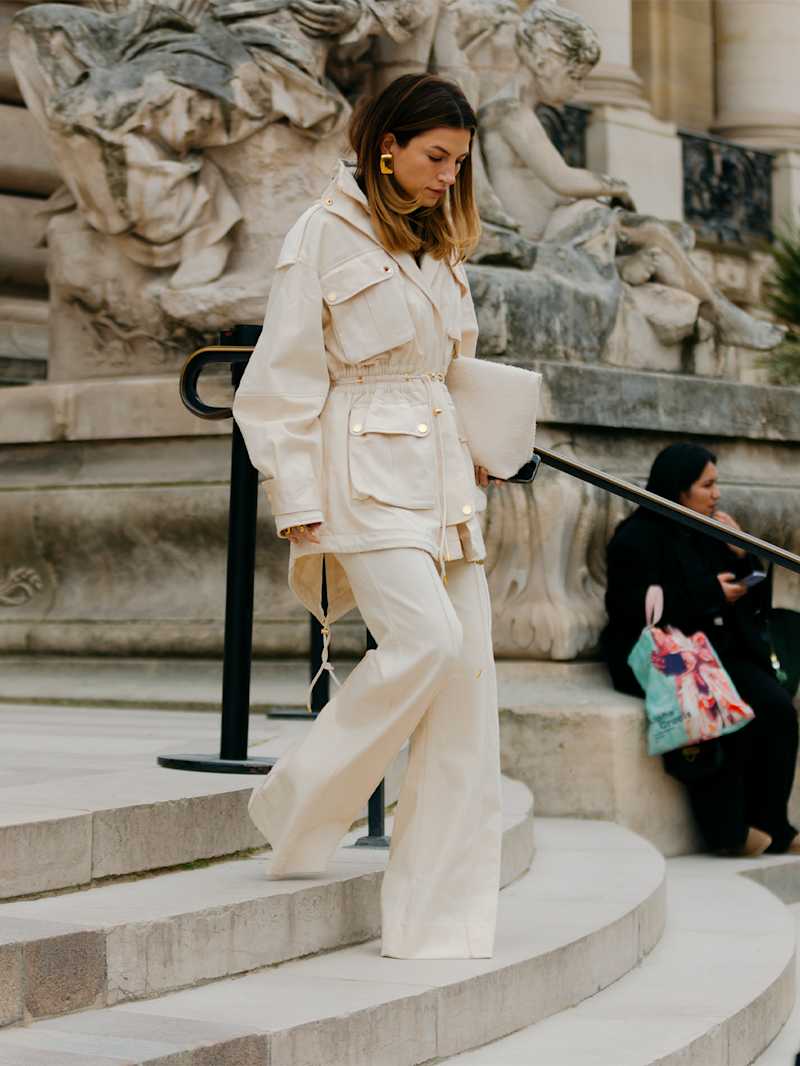 Frau in einem all-white-Look mit weißer Marlenehose und weißer Jacke