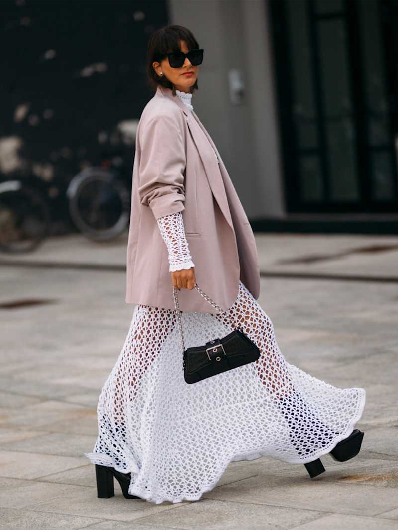 Große Frau in einem weißen Maxikleid aus Strick und einem Oversized-Blazer dazu