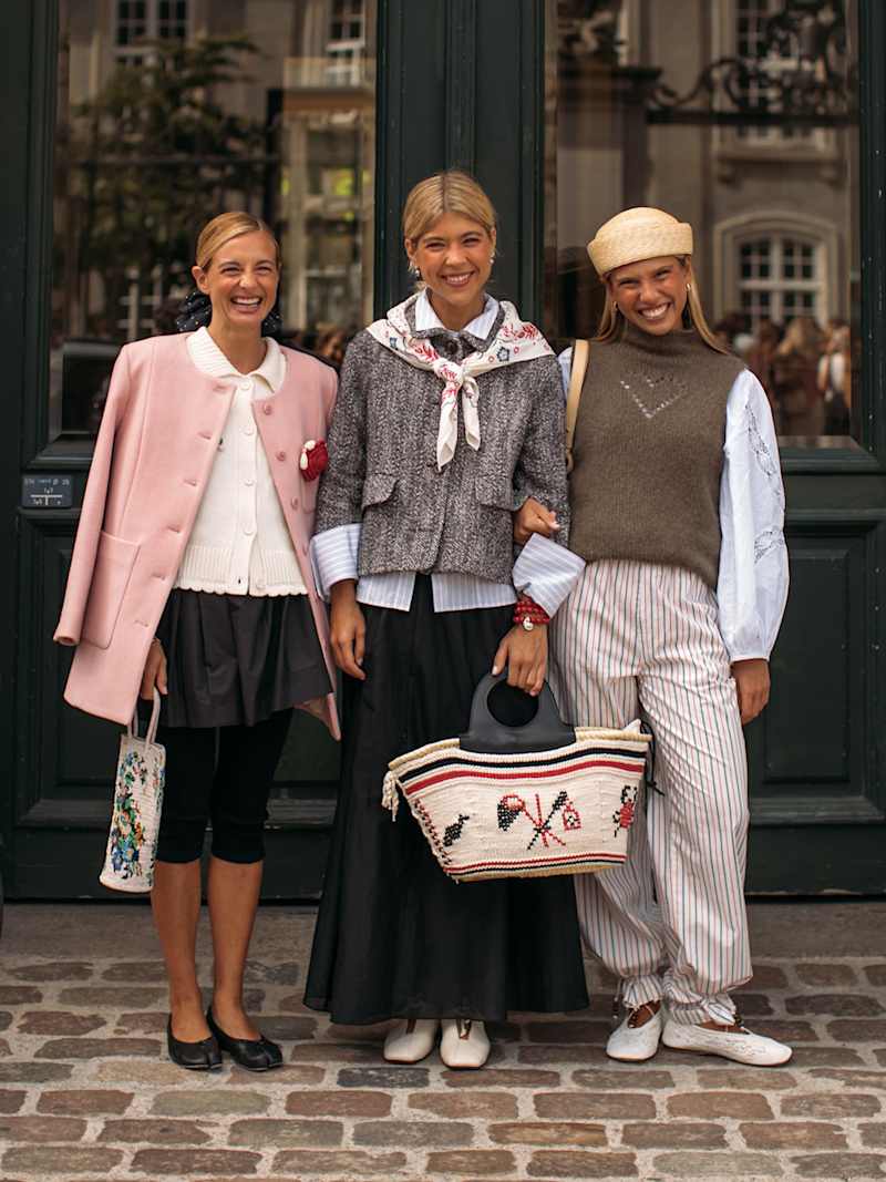 Drei Frauen stehen vor einer Haustür und tragen Modetrends für den Frühling 2026