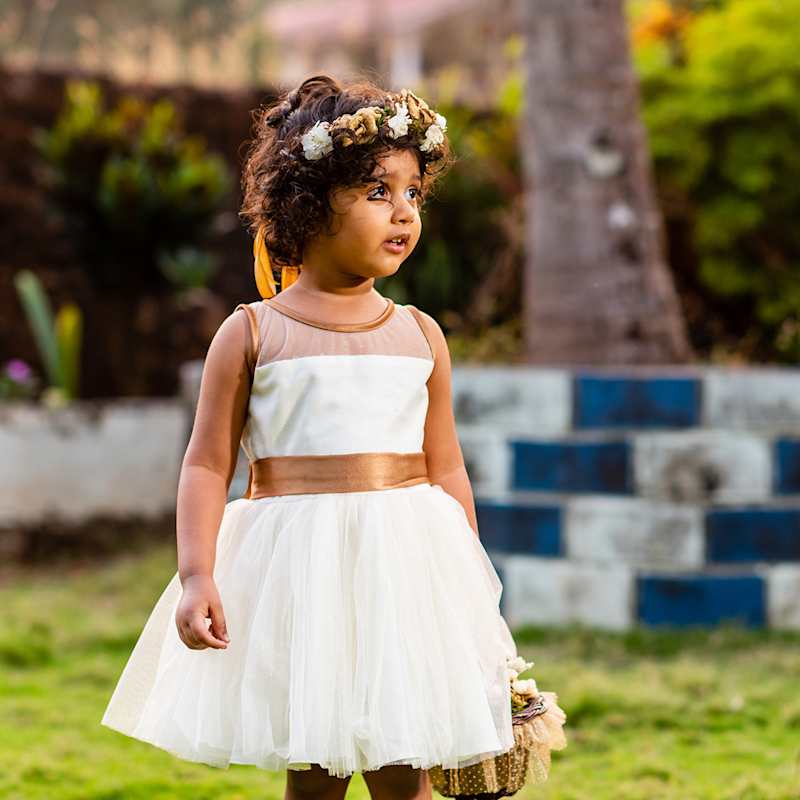 Ein Blumenmädchen trägt ein weißes Spitzenkleid und einen Blumenkranz im Haar