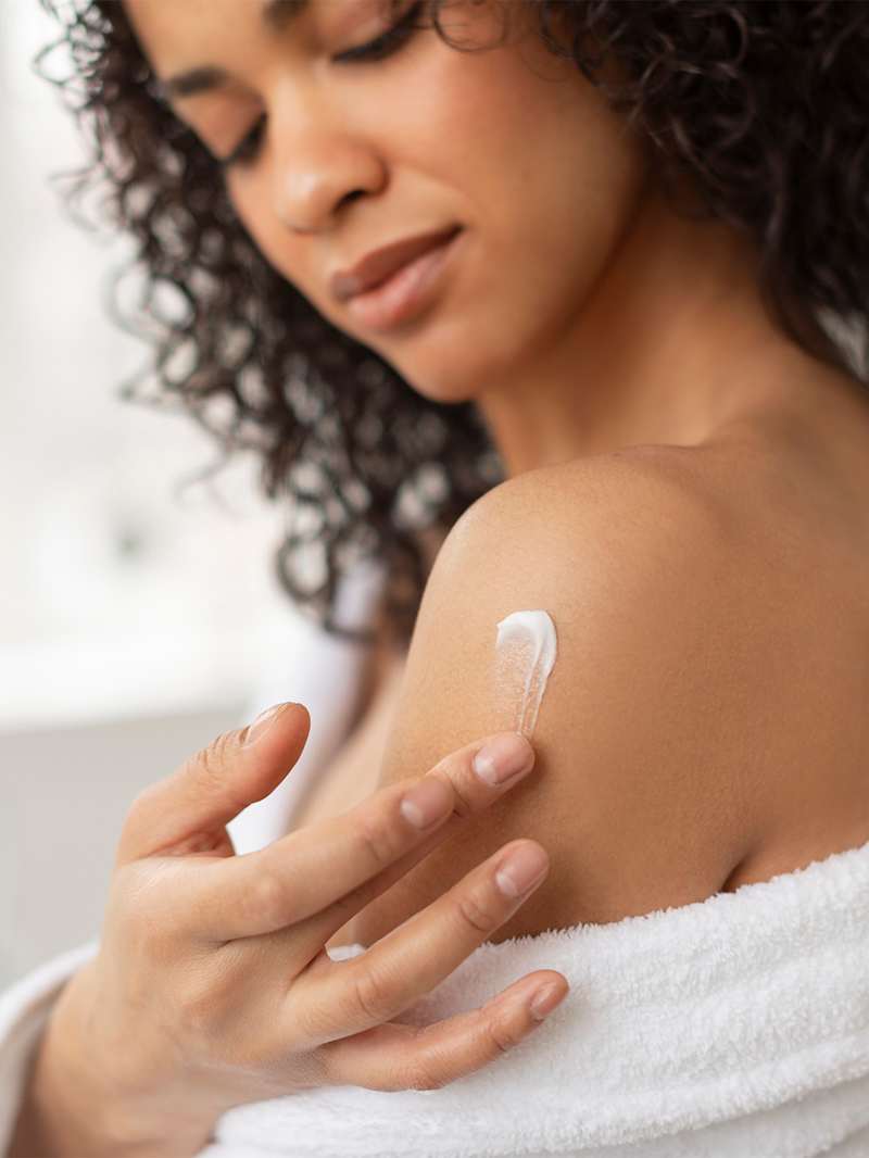 Brünette Frau pflegt ihre Haut mit Sheabutter