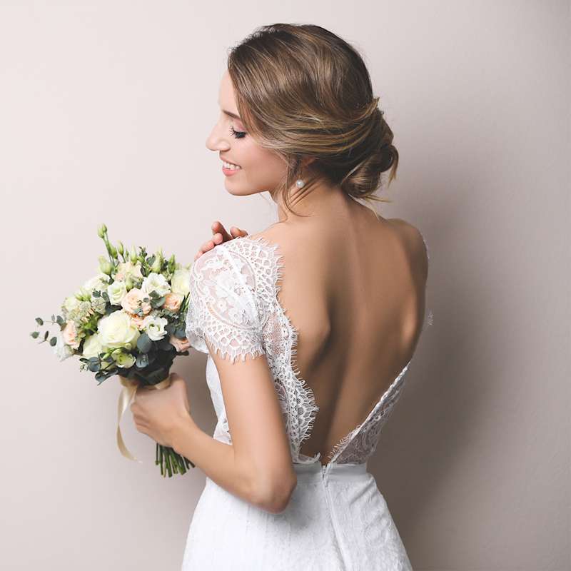 Frau im Hochzeitskleid von hinten mit hochgesteckter Brautfrisur