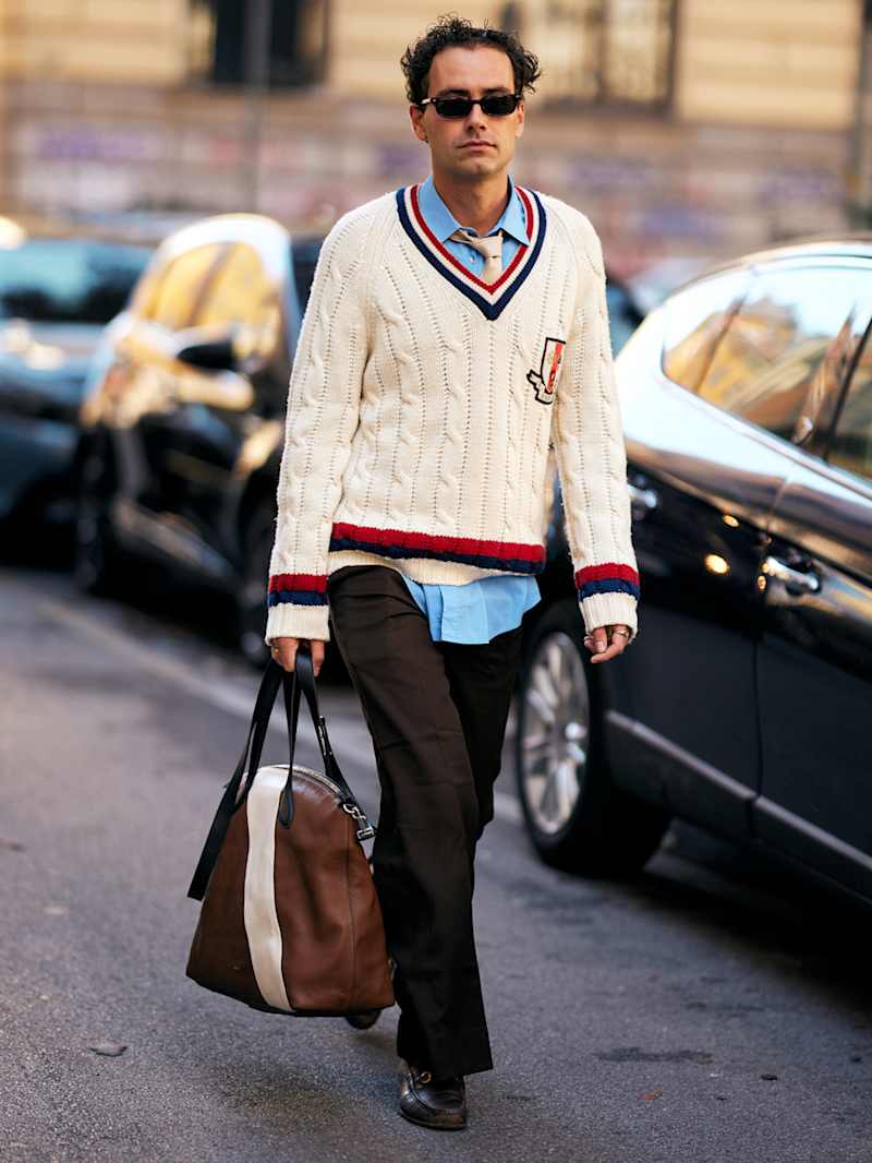 Mann trägt einen V-Ausschnitt Pullover aus cremefarbenen Zopfstrickmuster zu Stoffhose