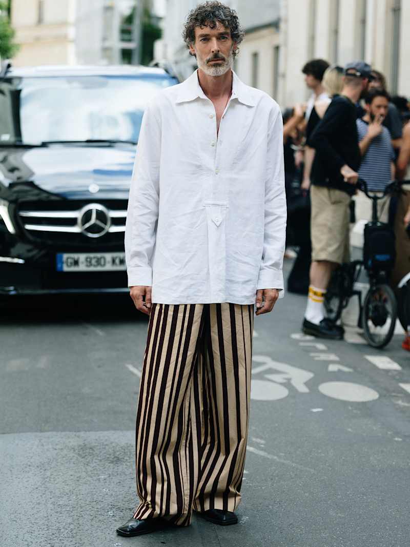 Mann trägt ein weißes Hemd zu einer Hose mit beige-schwarzen Streifen