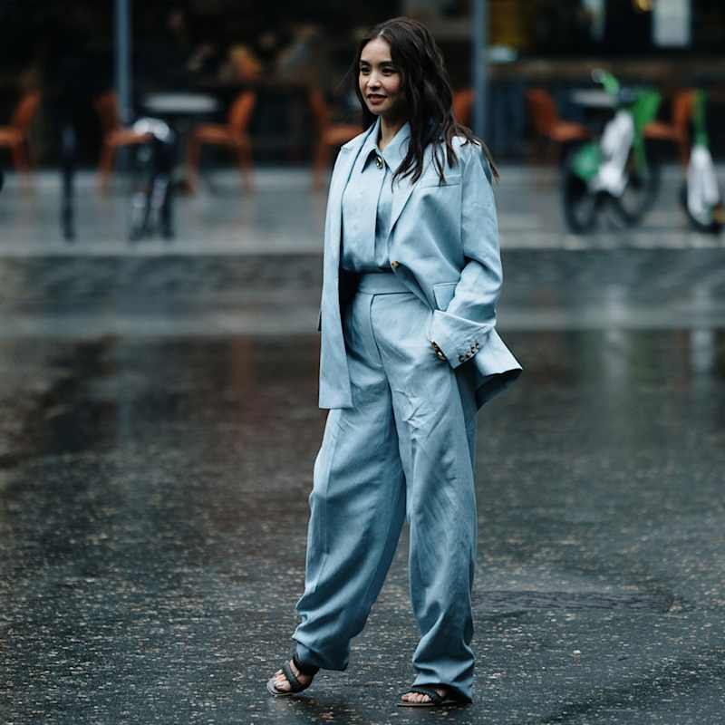 Dunkelhaarige Frau trägt hellblauen Satin-Zweiteiler mit Sandaletten