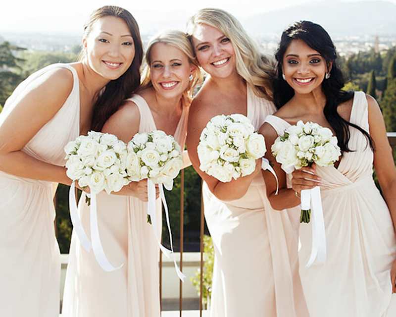 Vier Brautjungfern in rosa Kleidern mit Brautsträußen in der Hand