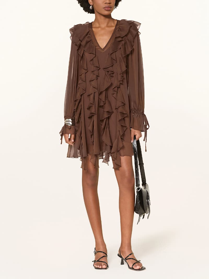 Frau trägt ein kurzes, braunes Kleid mit Volants 