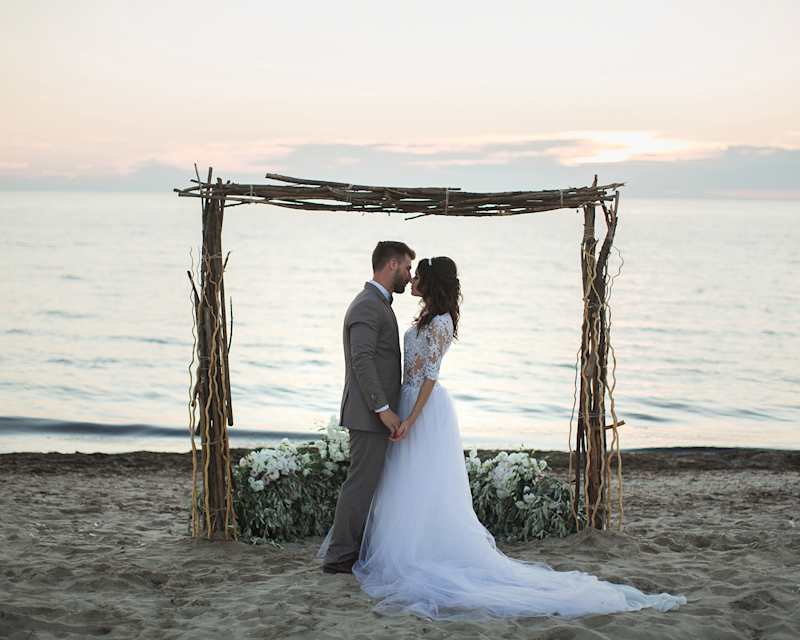 Brautpaar steht am Strand und hält sich an den Händen