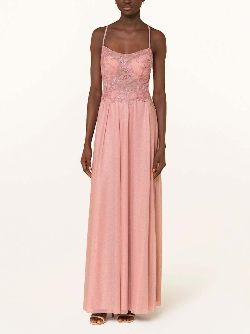 Frau trägt als Hochzeitsgast ein Ballkleid mit Spitze und Stickerei auf dem Oberteil in der Farbe Rosa