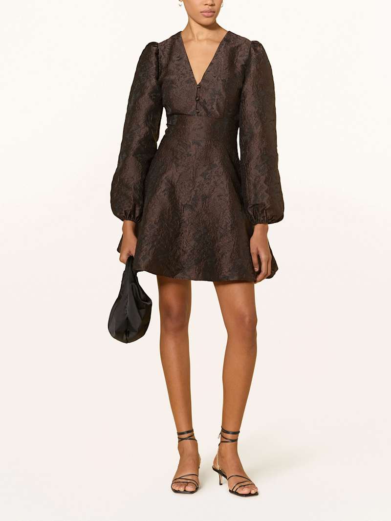 Frau trägt ein dunkelbraunes Cocktailkleid mit Jacquardmuster 