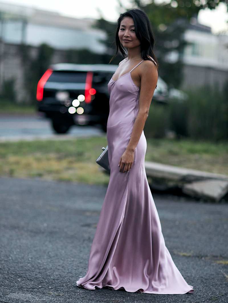Frau im Streetstyle-Look, trägt ein langes Satinkleid in der Farbe Flieder 