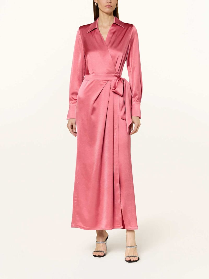 Frau trägt ein rosa Maxikleid mit Bindegürtel und Kragen