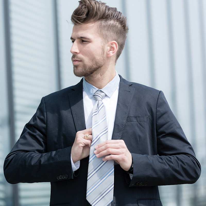 Ein eleganter Mann richtet ihre gestreifte Krawatte zum dunklen Anzug.